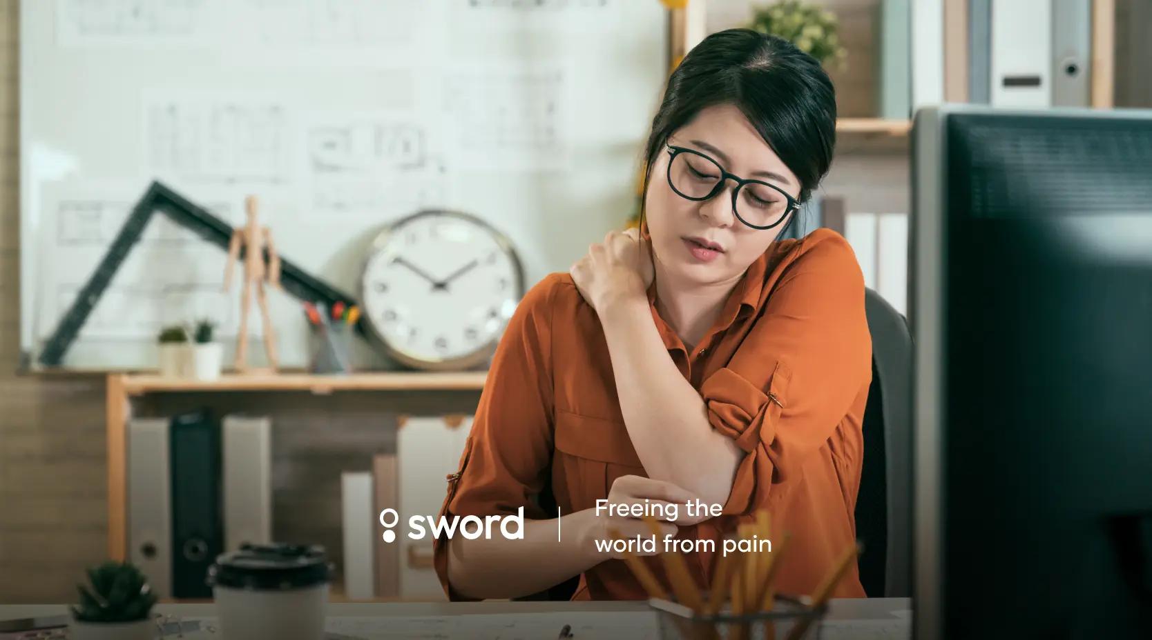 Woman in an orange shirt sitting at a desk, massaging her neck, with office supplies and a clock in the background. Text: "Freeing the world from pain."