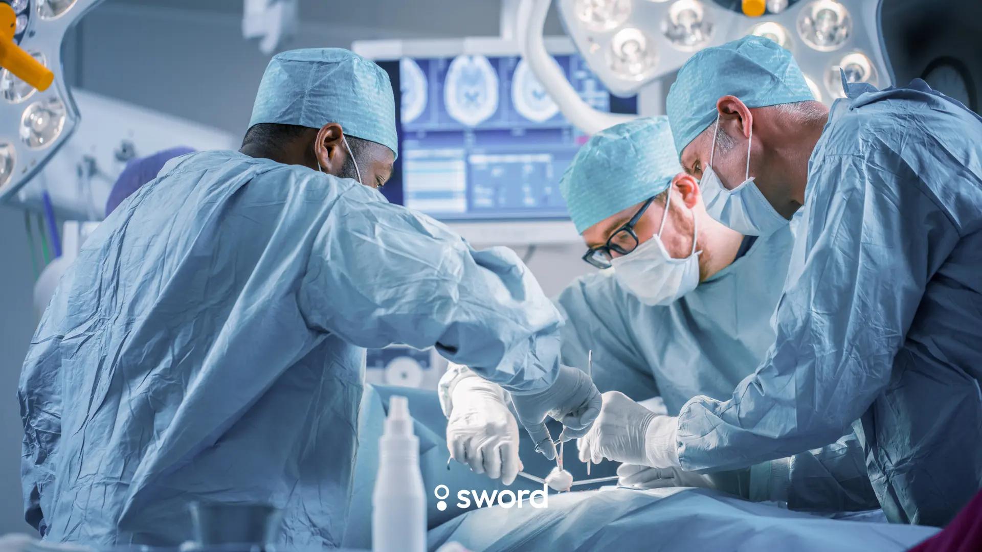 Three surgeons in blue scrubs and masks perform surgery in an operating room with bright lights and monitors.